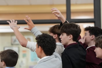 Several middle school students raising their hands
