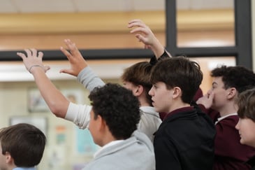 Several middle school students raising their hands